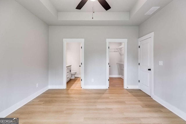 unfurnished bedroom with light wood-style flooring, baseboards, and a raised ceiling