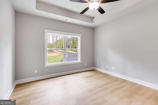 empty room with visible vents, baseboards, a raised ceiling, and wood finished floors