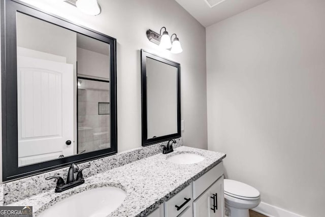 full bathroom featuring toilet, double vanity, baseboards, and a sink