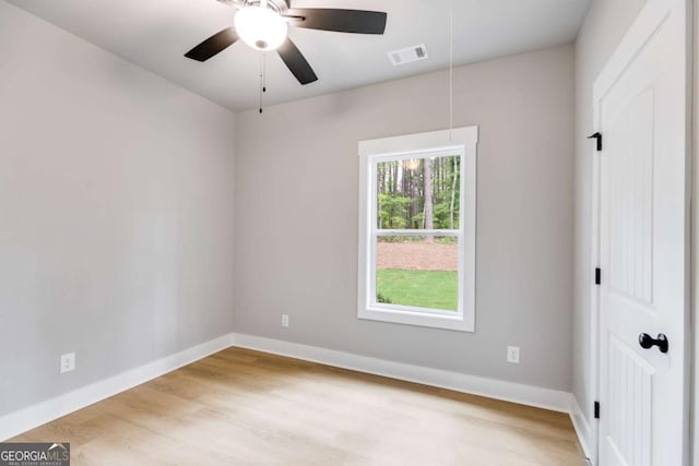 empty room with attic access, visible vents, baseboards, and wood finished floors