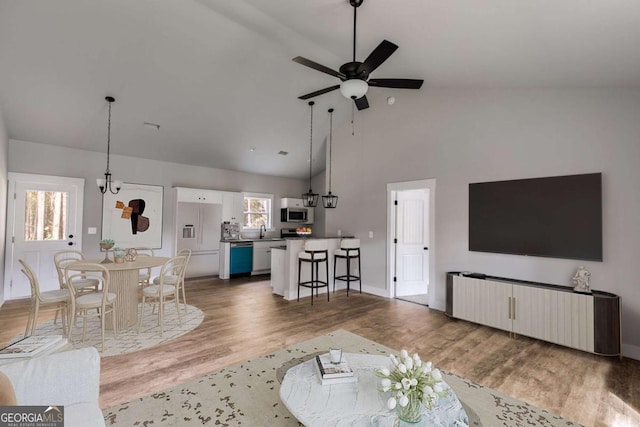 living room featuring baseboards, ceiling fan, high vaulted ceiling, and wood finished floors