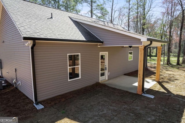 rear view of property featuring a shingled roof and a patio