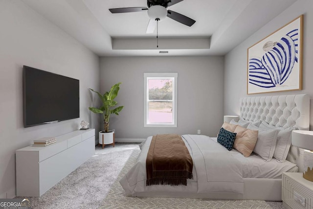 bedroom featuring carpet floors, a tray ceiling, and ceiling fan