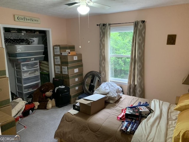 carpeted bedroom with ceiling fan and a textured ceiling