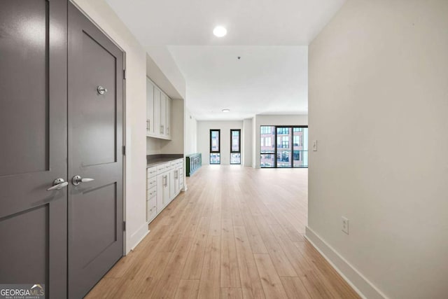 hall with light wood-style flooring and baseboards