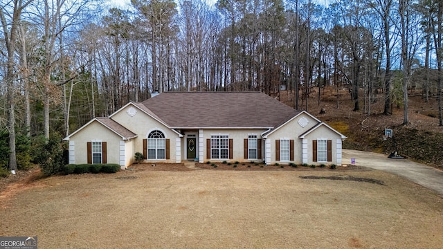 ranch-style house featuring driveway, a shingled roof, and stucco siding