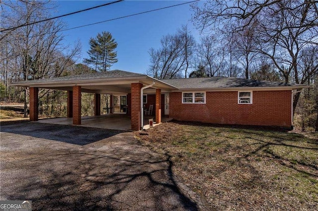 exterior space featuring driveway, brick siding, and an attached carport