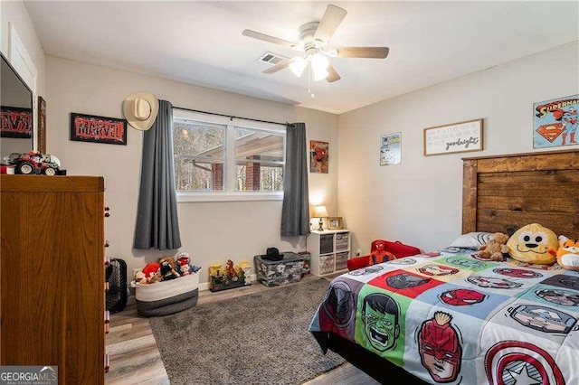 bedroom with ceiling fan, visible vents, and wood finished floors