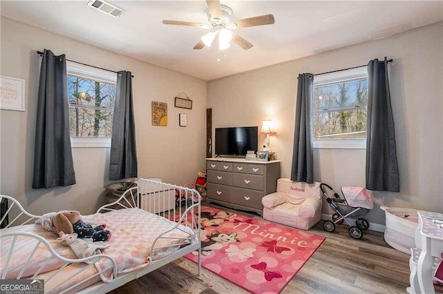 bedroom featuring baseboards, wood finished floors, visible vents, and a ceiling fan