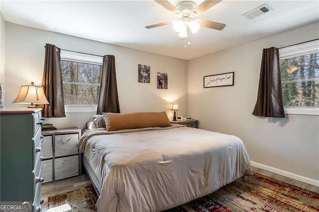 bedroom with ceiling fan, wood finished floors, visible vents, and baseboards