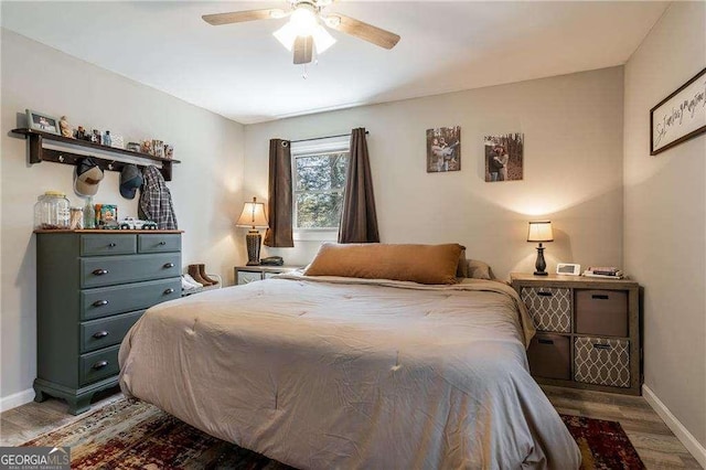 bedroom with a ceiling fan, baseboards, and wood finished floors