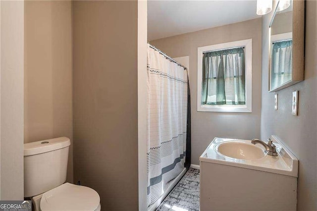 bathroom with a shower with shower curtain, vanity, toilet, and baseboards