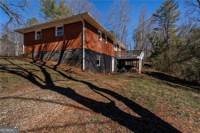 view of property exterior featuring brick siding and a wooden deck