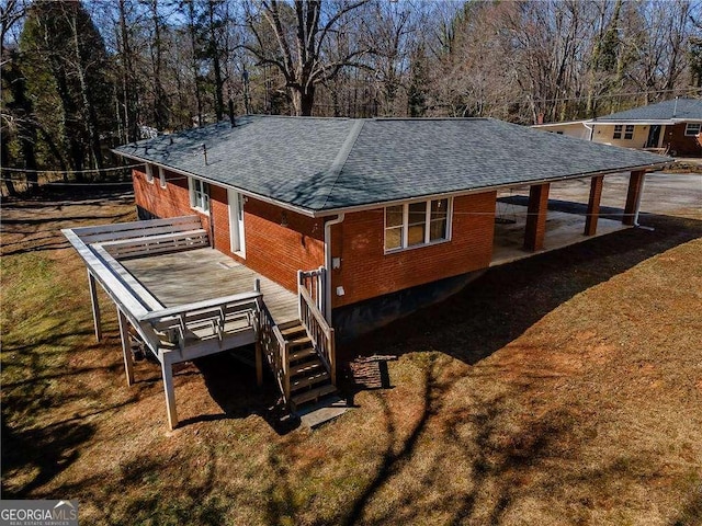 back of house featuring brick siding, a yard, roof with shingles, stairway, and a wooden deck