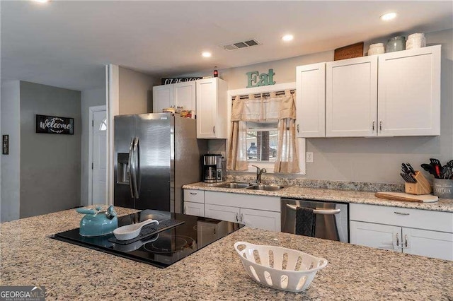 kitchen featuring visible vents, white cabinets, appliances with stainless steel finishes, light stone countertops, and a sink