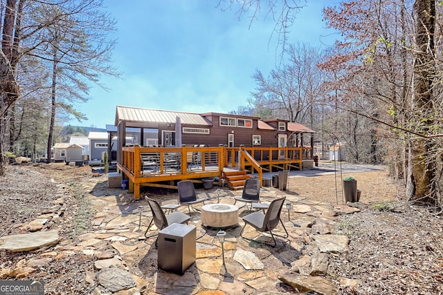 back of house with a deck, metal roof, a patio, and a fire pit