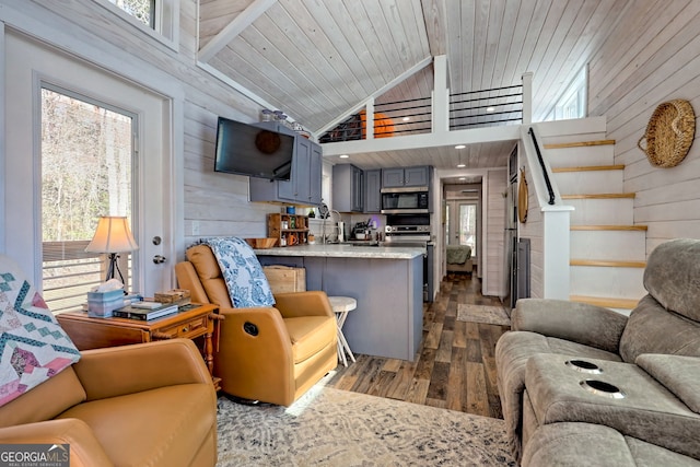 living room with dark wood-style flooring, a healthy amount of sunlight, wood walls, and stairway