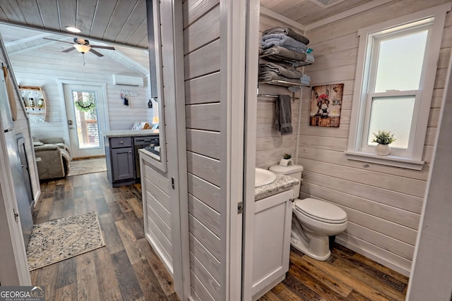 bathroom featuring a wall unit AC, toilet, wooden walls, wood finished floors, and vanity