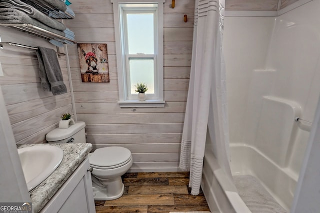 bathroom featuring vanity, wood walls, wood finished floors, and a wealth of natural light