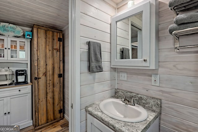 bathroom with wood ceiling, vanity, and wooden walls