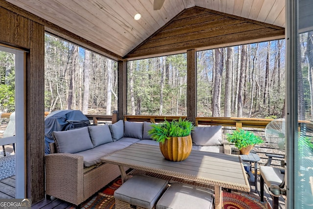 sunroom / solarium featuring lofted ceiling, wooden ceiling, and a wooded view