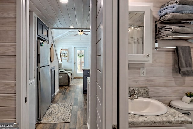 full bath featuring wooden ceiling, wooden walls, wood finished floors, vanity, and vaulted ceiling