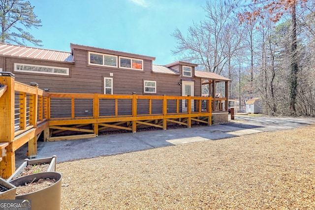 back of property with metal roof and a wooden deck