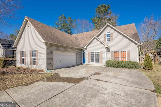 traditional home with concrete driveway, roof with shingles, and an attached garage