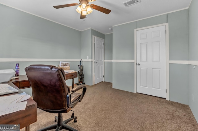 carpeted home office featuring crown molding, visible vents, and a ceiling fan