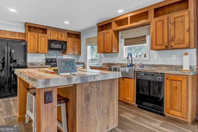 kitchen featuring a sink, light wood-style flooring, black appliances, and open shelves