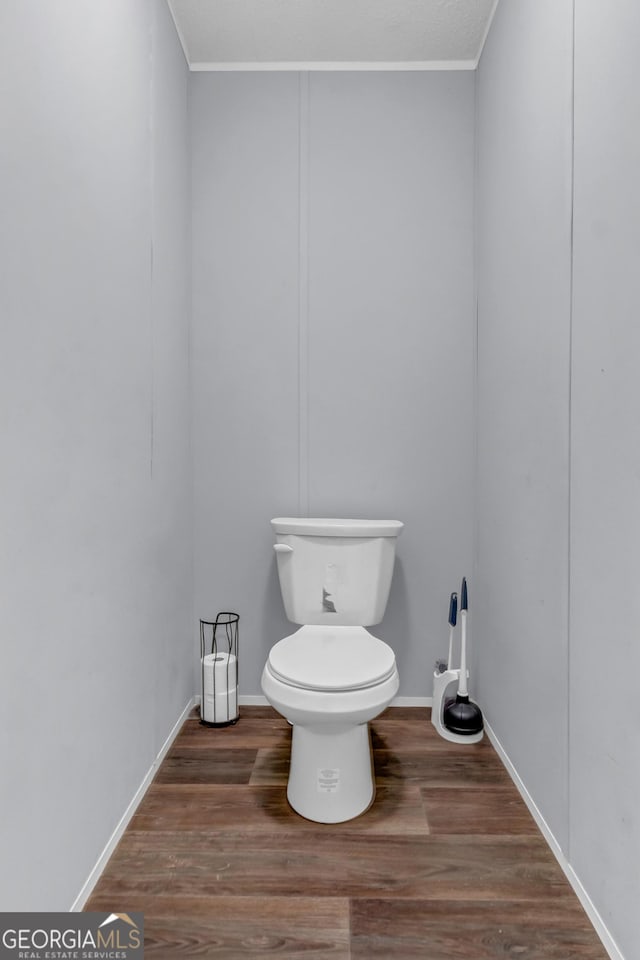 bathroom with crown molding, wood finished floors, toilet, and baseboards