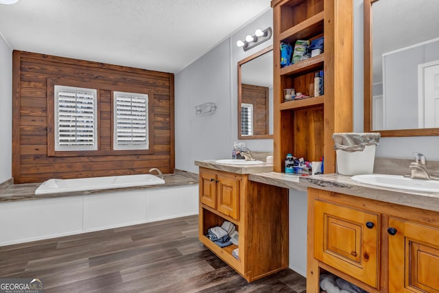 full bathroom featuring two vanities, a sink, a bath, and wood finished floors