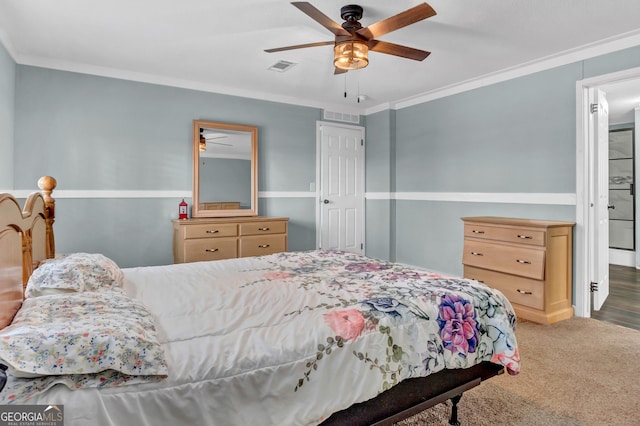 carpeted bedroom featuring a ceiling fan, visible vents, and crown molding