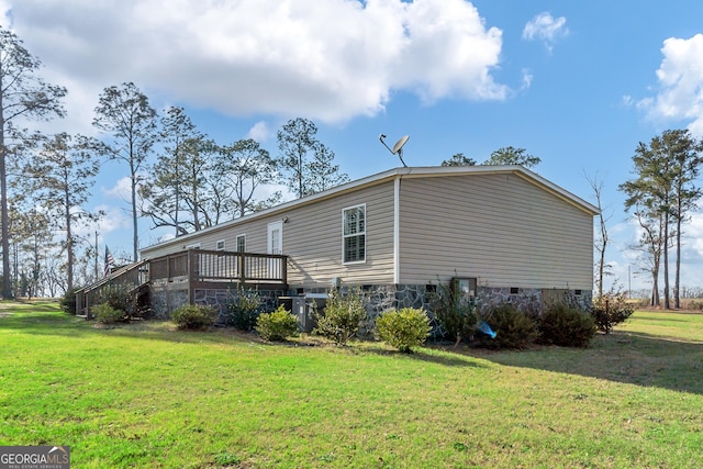 view of side of home with crawl space, a yard, and a deck