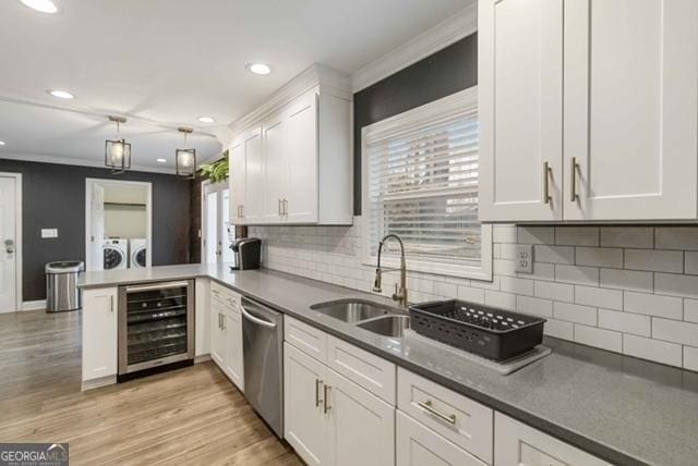 kitchen featuring beverage cooler, a peninsula, white cabinets, stainless steel dishwasher, and washing machine and clothes dryer