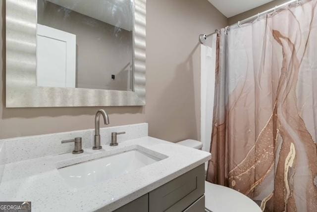 bathroom featuring a shower with shower curtain, vanity, and toilet