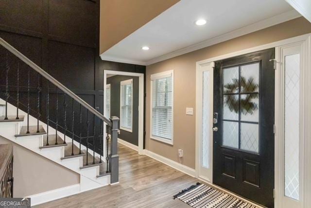 entryway featuring baseboards, ornamental molding, wood finished floors, stairs, and recessed lighting