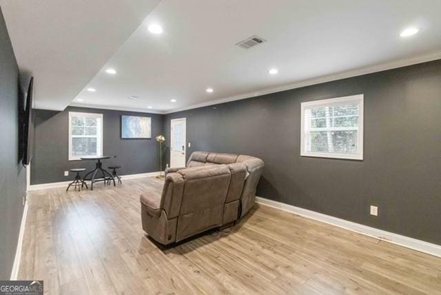 living area featuring baseboards, visible vents, light wood-style flooring, crown molding, and recessed lighting