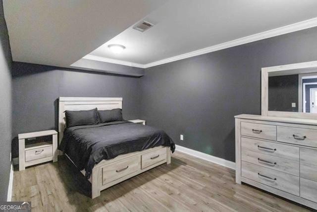 bedroom featuring visible vents, crown molding, baseboards, and wood finished floors