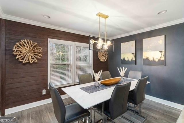 dining room with baseboards, a chandelier, crown molding, and wood finished floors