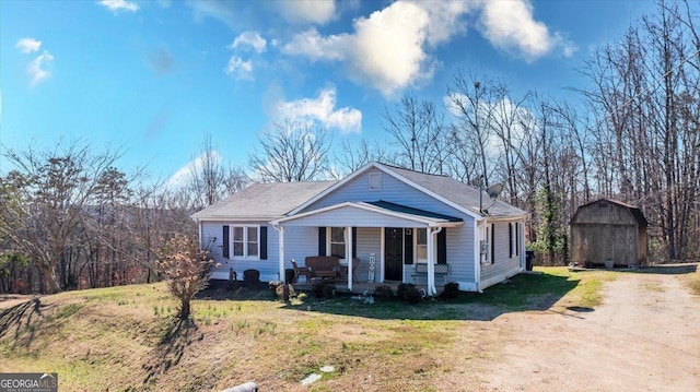 bungalow featuring a porch, a front yard, an outdoor structure, and driveway