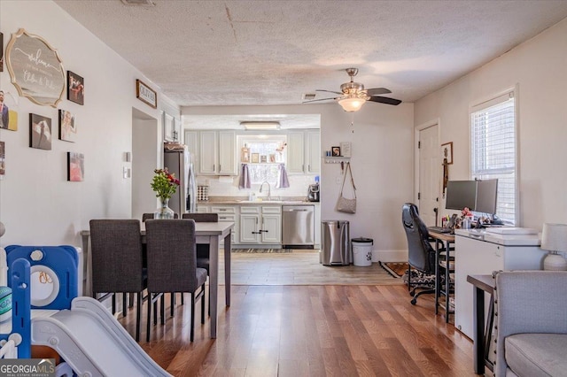 home office with a textured ceiling, a sink, light wood-style flooring, and a ceiling fan