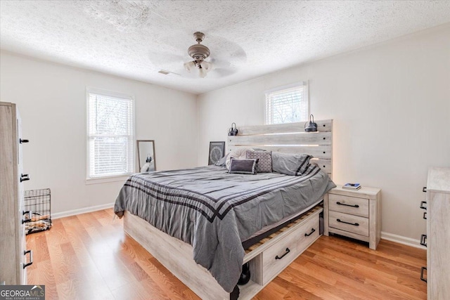 bedroom with light wood-style floors, a ceiling fan, baseboards, and a textured ceiling