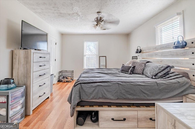 bedroom featuring a textured ceiling, light wood finished floors, visible vents, and a ceiling fan