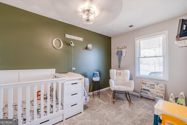 bedroom featuring visible vents, light carpet, a crib, and baseboards