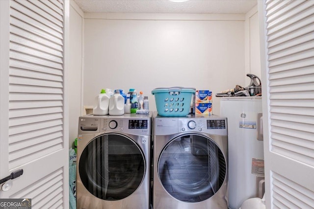 washroom with laundry area, washing machine and dryer, a textured ceiling, and electric water heater