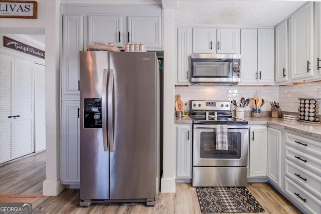 kitchen with light wood-style floors, tasteful backsplash, stainless steel appliances, and a textured ceiling