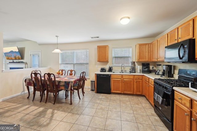 kitchen featuring light tile patterned floors, light countertops, black appliances, visible vents, and a sink