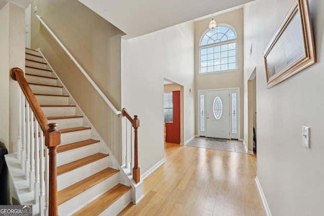 foyer entrance with stairs, baseboards, and hardwood / wood-style floors