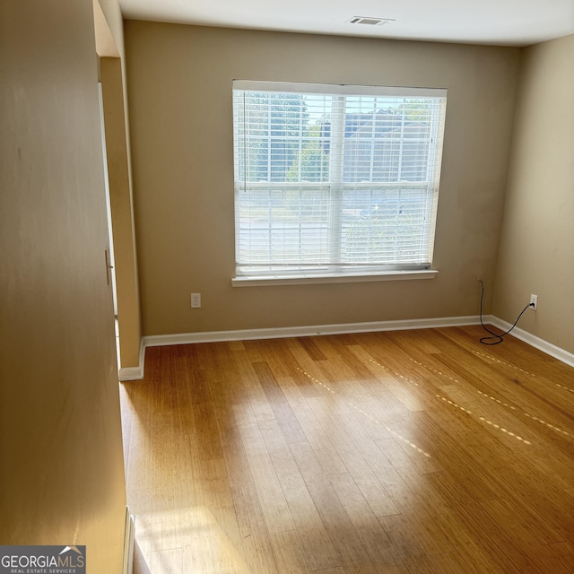 empty room with visible vents, baseboards, and wood finished floors